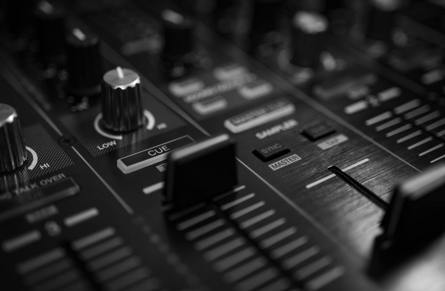 world music w elektronice - High-contrast close-up of an audio mixer with sliders and knobs in a black and white tone.