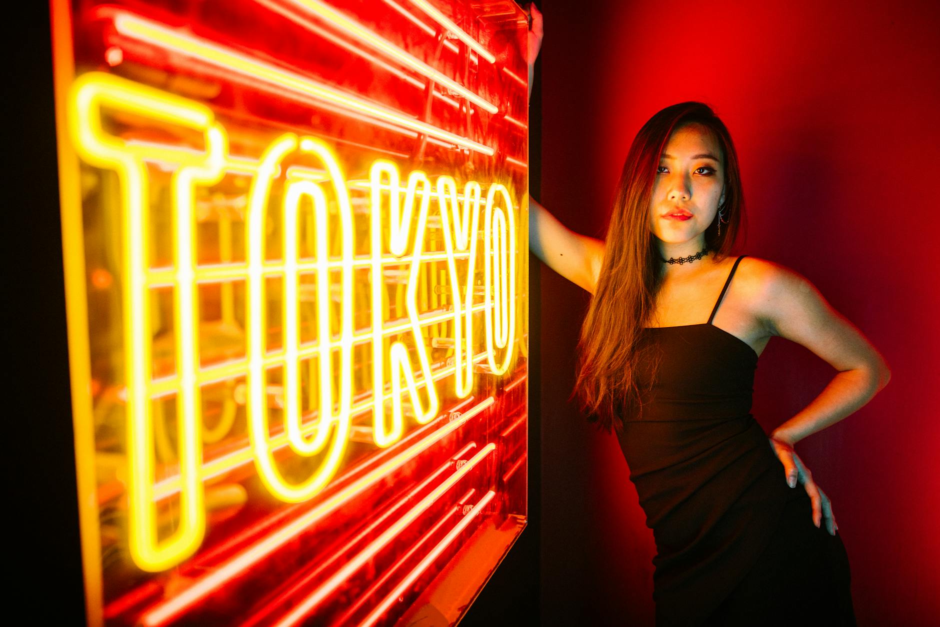 Gen Z oczekuje immersywnych doświadczeń - A stylish woman poses by a vibrant Tokyo neon sign, exuding modern urban nightlife.