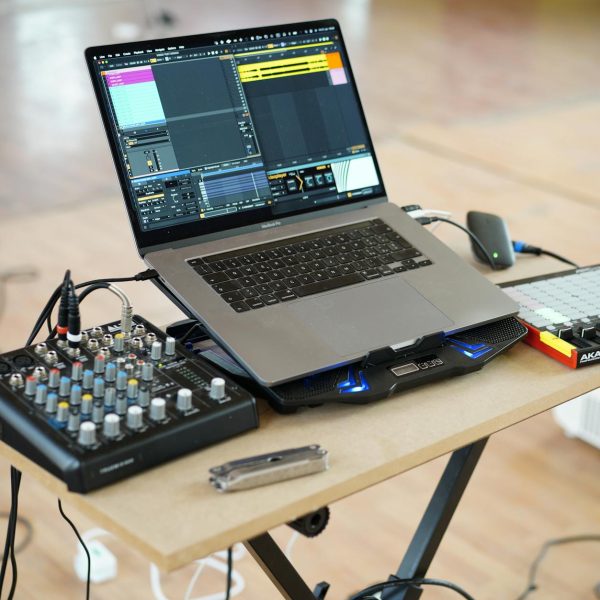 AlphaTheta DJM-V5 setup guide - A home music production setup with a laptop, mixer, and controller on a desk.
