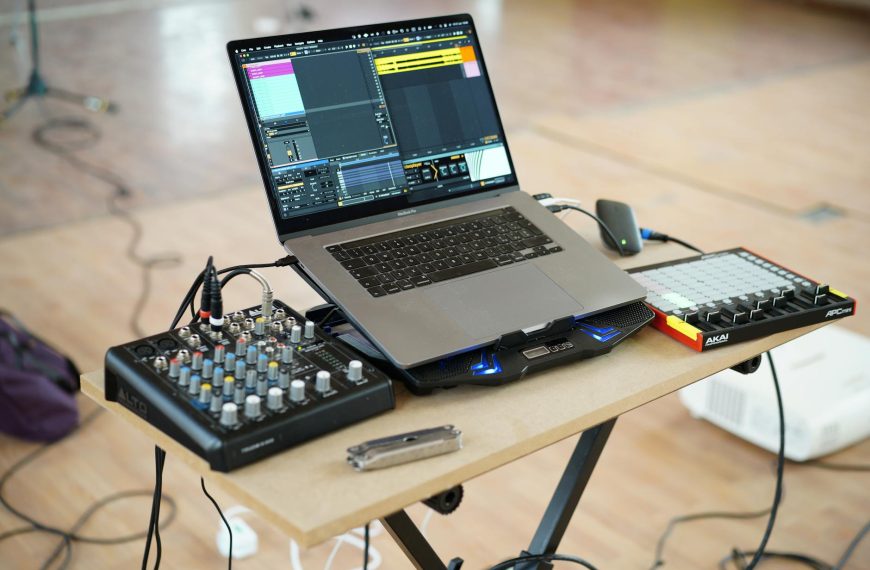 AlphaTheta DJM-V5 setup guide - A home music production setup with a laptop, mixer, and controller on a desk.