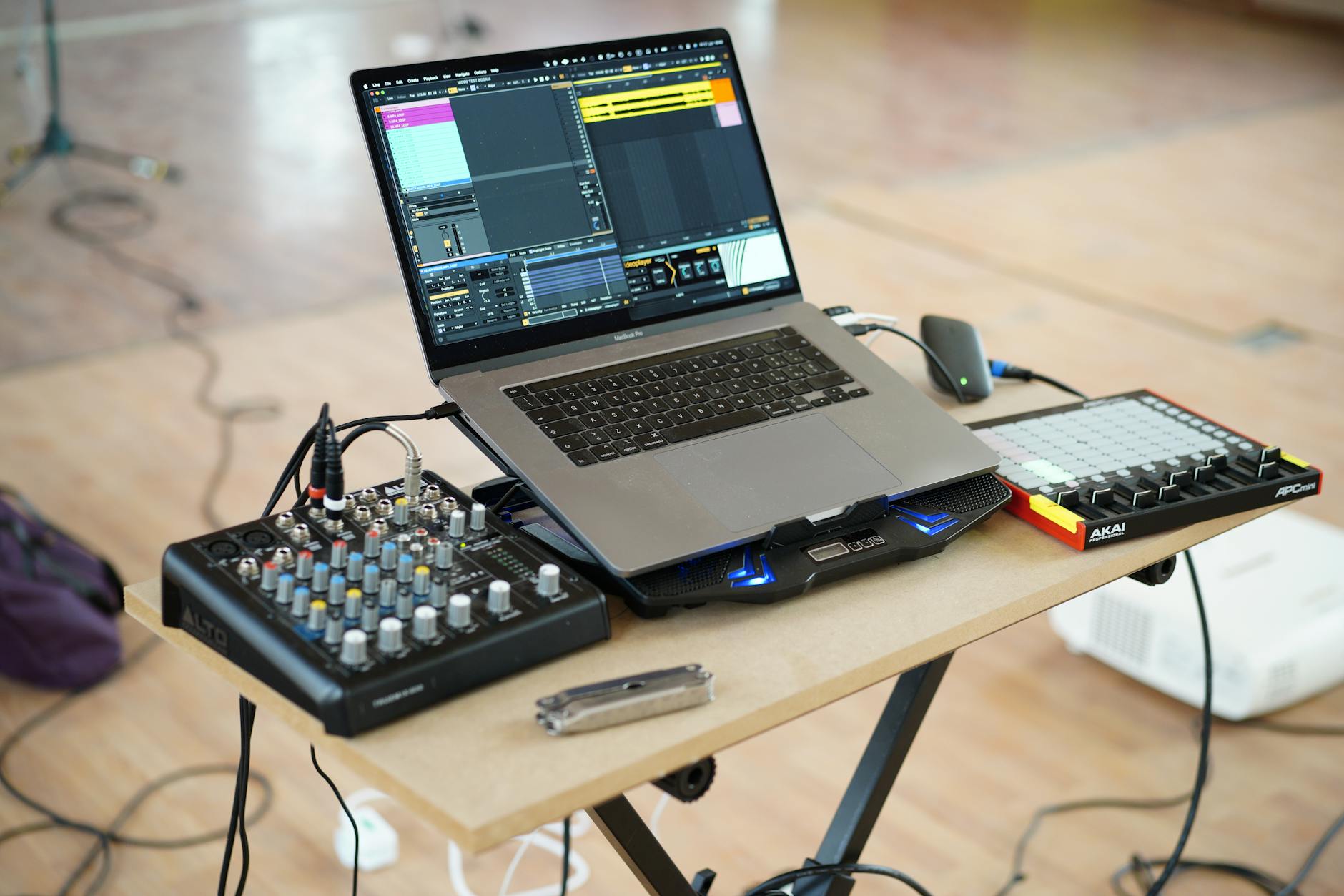 AlphaTheta DJM-V5 setup guide - A home music production setup with a laptop, mixer, and controller on a desk.