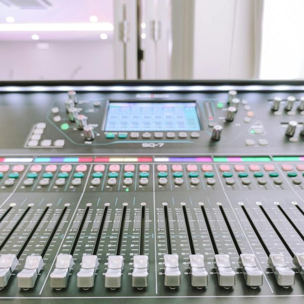 AI mixing tools - Close-up view of a digital audio mixer in a recording studio environment.