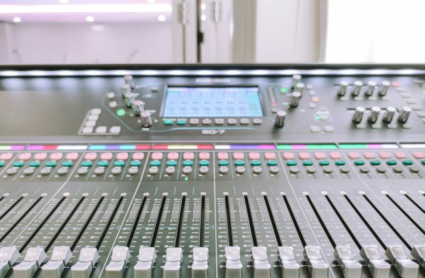 AI mixing tools - Close-up view of a digital audio mixer in a recording studio environment.