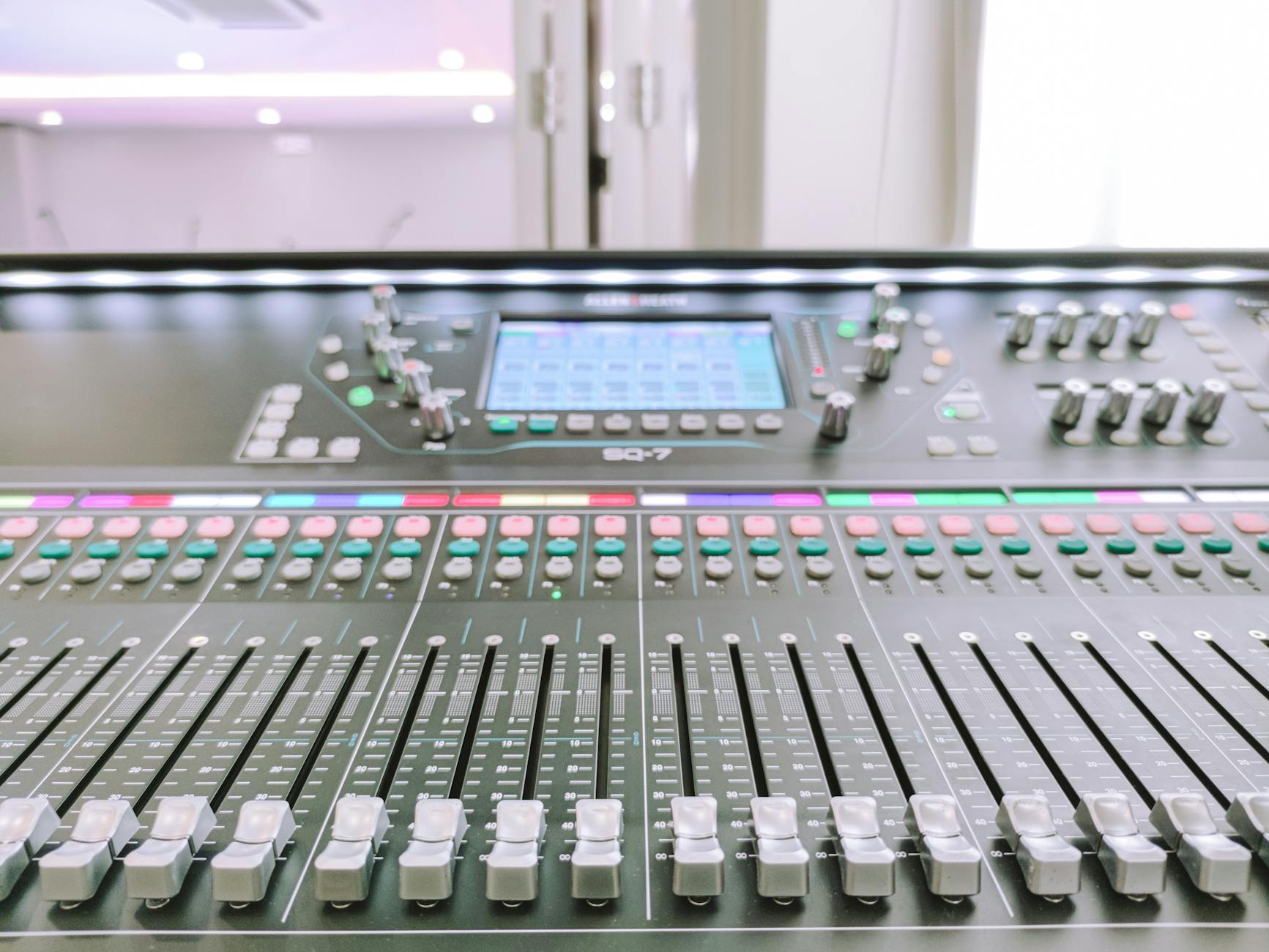 AI mixing tools - Close-up view of a digital audio mixer in a recording studio environment.