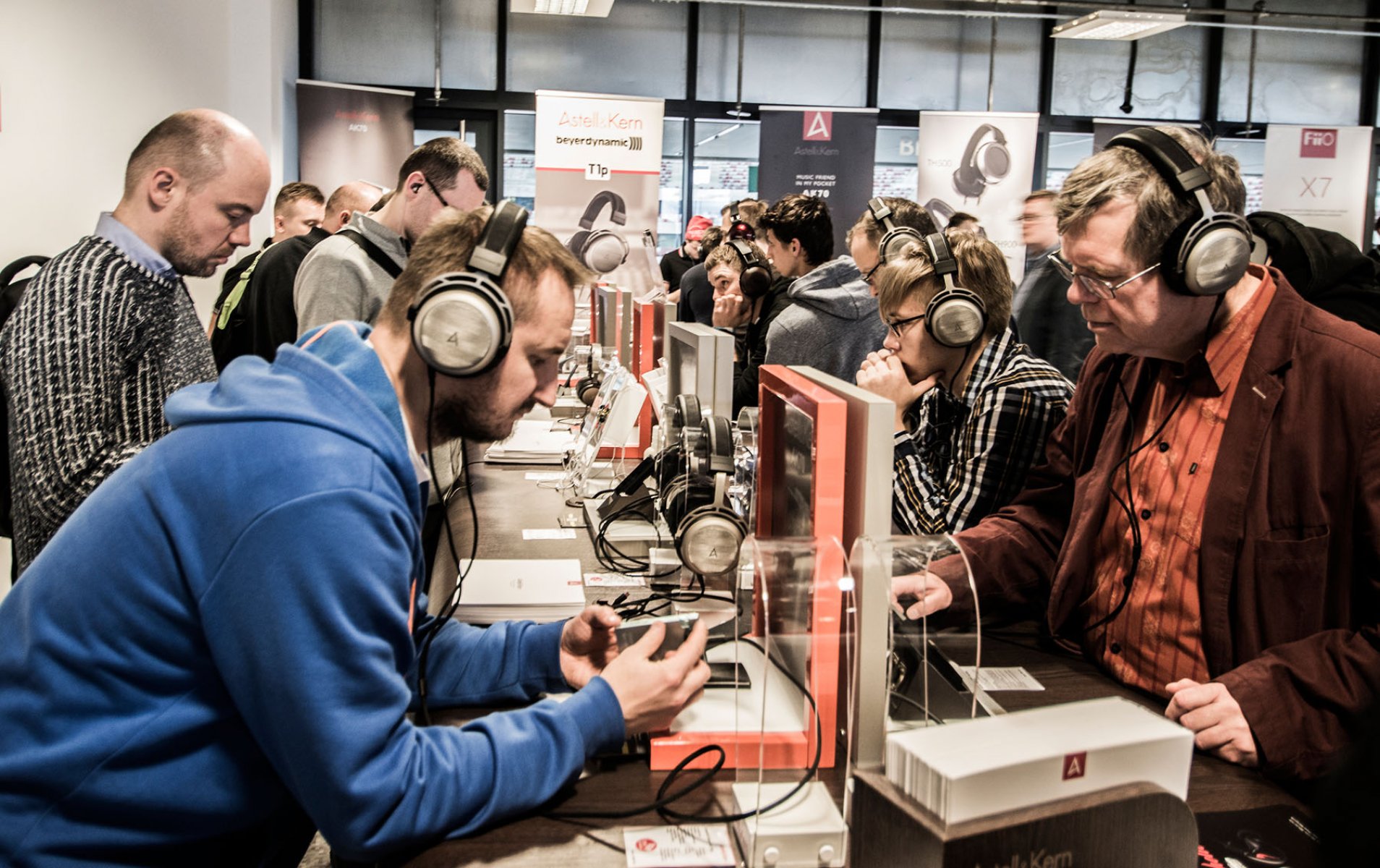 Uczestnicy Audio Video Show porównują słuchawki przy stanowiskach odsłuchowych