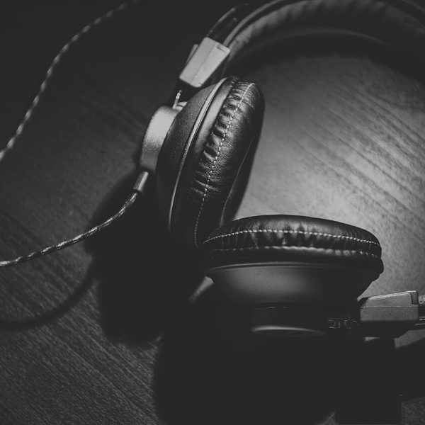 Czarno-białe zdjęcie słuchawek na drewnianym blacie. Ilustracja poglądowa artykułu o streamingu.