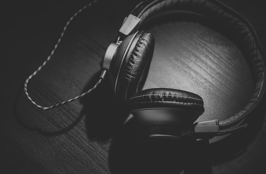 Czarno-białe zdjęcie słuchawek na drewnianym blacie. Ilustracja poglądowa artykułu o streamingu.